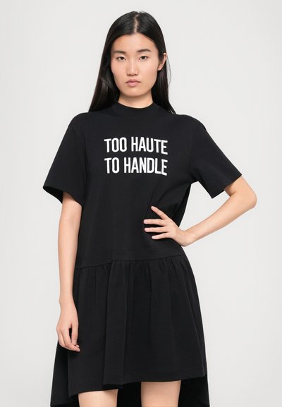 Must mustriga must dress, lühikeste varrukatega, ümarate kaelustega ja volangse seelikuosaga. Ees on tekst "TOO HAUTE TO HANDLE" valgega.