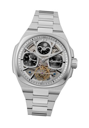 Montre en acier inoxydable argenté avec un design squelette. Sous-cadrans noirs, rouages dorés visibles et index horaires. Présente un bracelet texturé.