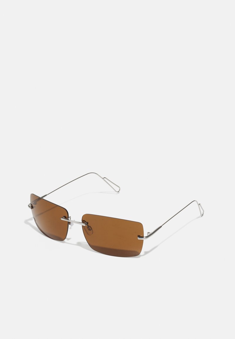 Óculos de sol retangulares castanhos com montura fina em fio de prata e suportes para o nariz. As lentes são planas e ligeiramente tintadas.