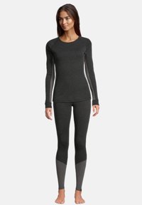 Långärmad, svart termotröja som matchas med svarta och grå leggings. Har en figurnära passform, kontrasterande ärmar och en mjuk textur.