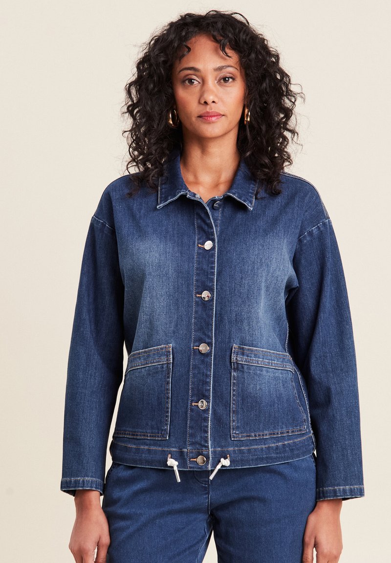 Donkerblauwe denimjas met knoopsluiting, twee grote voorkwasten, verstelbare trekkoordzoom en een klassieke kraag. Zachte textuur.