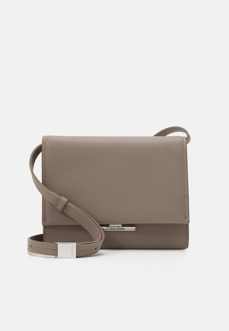 Compact grijze crossbodytas van gestructureerd synthetisch materiaal, voorzien van een flapsluiting, verstelbare band en zilverkleurige hardware accenten.