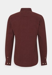 Chemise à manches longues en tissu bourgogne profond, avec un col classique, un ourlet droit et des poignets boutonnés. Subtil motif texturé visible.