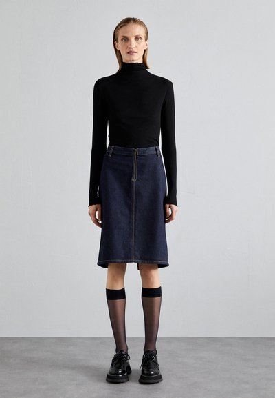 Top negru cu mâneci lungi, fustă A-line din denim închis la culoare cu fermoar frontal, șosete negre semitransparente până la genunchi cu benzi solide și pantofi negri cu șireturi.