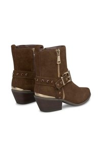 Bruine suède enkelboots met een goudkleurige gesp en studs, zijritsen en een gestapelde hak. Heeft een afgeronde neusontwerp.