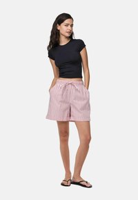 Černé přiléhavé tričko spárované s růžovými a bílými pruhovanými kraťasy s elastickým pasem, bočními kapsami a volným střihem.