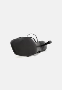 Svart sko med kvadratig tå, texturerad sula och tunna remmar. Materialet verkar slätt med en glänsande yta; minimalistisk design.
