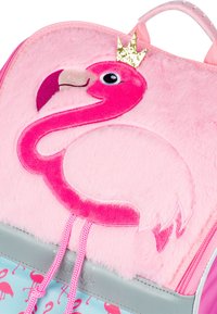 Rosa Rucksack mit einem plüschigen Flamingo-Design, weicher Textur, goldener Krone Detail und hellblauem Grund mit Flamingo-Muster.