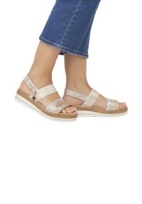 Sandales plateforme en beige métallisé, présentant une bride tissée, une sangle de cheville réglable et une semelle en caoutchouc texturée avec une légère courbure.