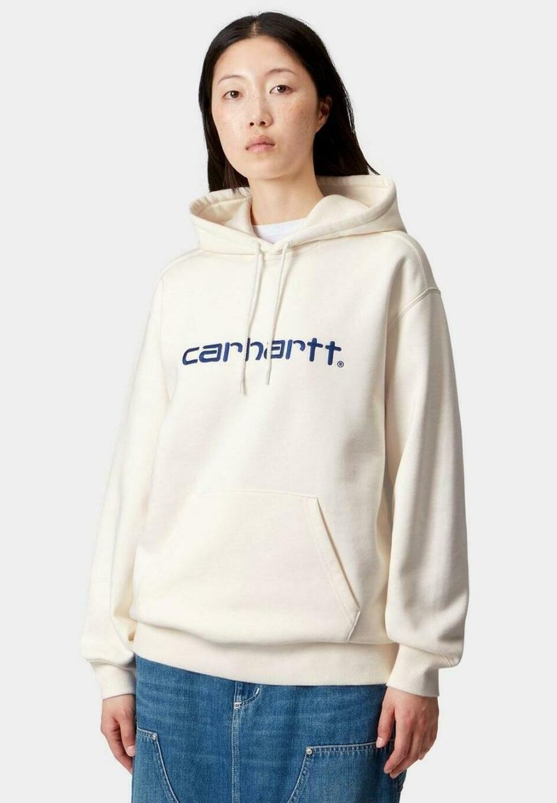 Sudadera color crema hecha de material suave, con un bolsillo frontal y un logo azul marino en el pecho. Capucha con cordones y corte relajado.