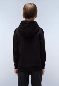 Zwarte hoodie met een kangoeroezak en geribbelde manchetten. Bevat een capuchon met trekkoord en heeft een gladde textuur, gedragen met zwarte broek.