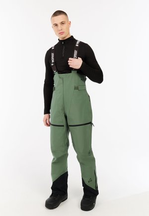 Groene skibroek met zwarte accenten, verstelbare banden en meerdere ritssluitingen, gemaakt van duurzaam, weerbestendig materiaal.