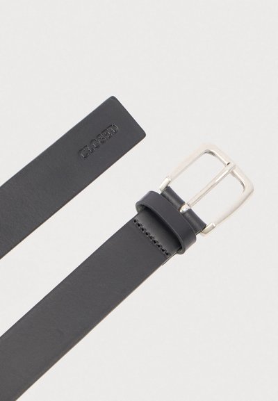 Μαύρη δερμάτινη ζώνη με ασημένια ορθογώνια αγκράφα και την ένδειξη "CLOSED" σε ανάγλυφο κοντά στο τέλος της, τοποθετημένη επίπεδα σε ανοιχτό γκρι φόντο.