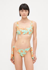 Ensemble de bikini en vert menthe, orné de motifs floraux orange. Le haut possède des bretelles larges et un décolleté carré ; le bas a un détail de lien sur le côté.