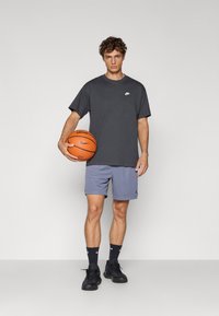 Grå Nike T-shirt med logo, lyseblå shorts, sorte sneakers og basketball. Enkel design, behagelig pasform, egnet til sport.