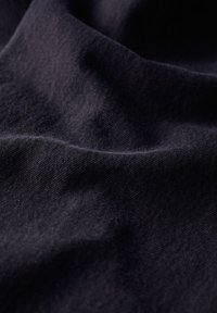 Tejido de un oscuro color navy con un suave tejido texturizado, que muestra sutiles arrugas y pliegues. El material parece duradero y flexible.