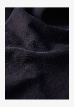 Dunkelblaues Gewebe mit einer weichen, strukturierten Webart, die subtile Falten und Knicke zeigt. Das Material wirkt langlebig und flexibel.