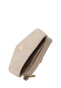Beżowy, zamszowy portfel z zamkiem błyskawicznym, mosiężnymi akcesoriami i prostym wzornictwem. Posiada wewnętrzną kieszonkę na monety.