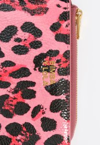 Clutch de leopardo en tonos rosa y negro con acabado texturizado, acento de logo dorado y cierre de cremallera. Presenta una superficie lisa y brillante.