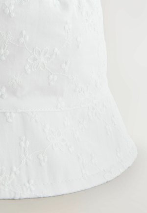 Pălărie albă dintr-un material ușor, cu broderie florală și o textura moale, fină. Marginile sunt ușor curbate.