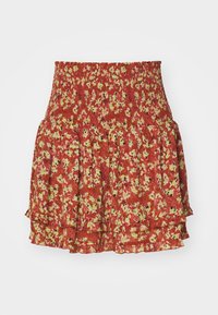Jupe rouge à fleurs avec une taille smockée, des volants superposés et un motif de petites fleurs jaunes et noires sur un fond texturé.