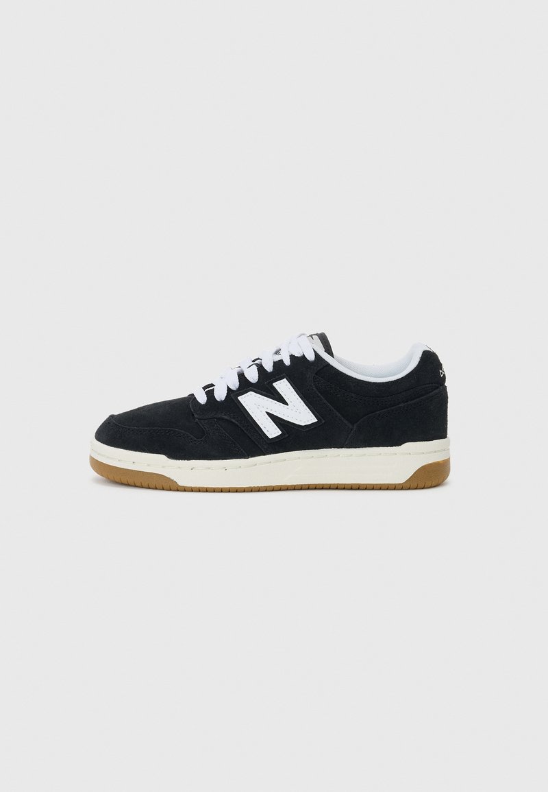 Crni suede tenisice s bijelim vezicama i logotipom. Imaju kremastu srednju podlogu i smeđi gumeni potplat. Niska konstrukcija, teksturirani gornji dio.