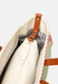 Sac fourre-tout ouvert avec extérieur tissé multicolore, anses en cuir fauve et pochette blanche zippée fixée à l'intérieur avec une lanière en cuir et un anneau métallique.