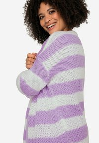 Strickjacke in Weiß und Lavendelstreifen. Verfügt über einen lockeren Schnitt mit strukturiertem Stoff und gerippten Bündchen. Weiches, atmungsaktives Material.