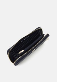 Navy zip-around wallet with gold-tone hardware, multiple card slots, a zippered compartment, and a textured finish. Interior logo visible.