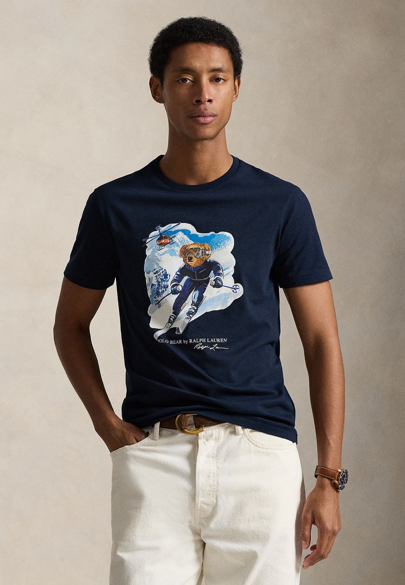 Navy cotton t-shirt featuring a graphic of a bear skiing, surrounded by snow and mountains, with the text "POLO BEAR by RALPH LAUREN."
