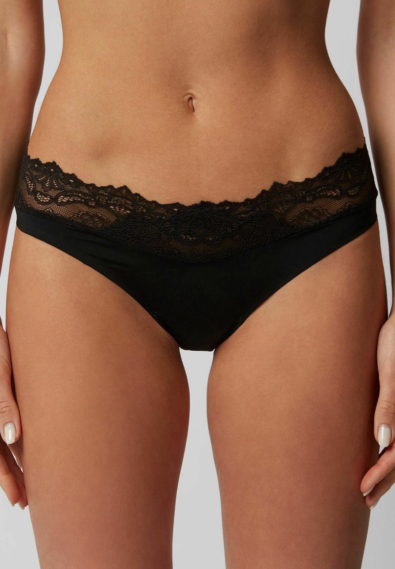 Schwarze Unterhose mit einem gewellten Spitzensaum, einem glatten Stoffkörper und einem Design mit minimaler Abdeckung, das aufwendige Spitzenverzierungen aufweist.