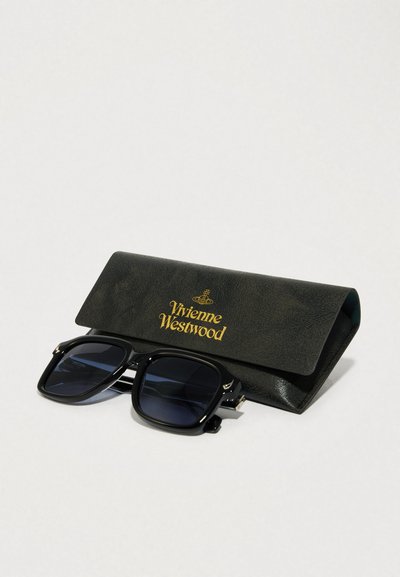 Fekete napszemüveg, nagy négyzet alakú keretekkel, mellette egy fekete műbőr tok, aranyszínű "Vivienne Westwood" felirattal. A lencsék sötétek.