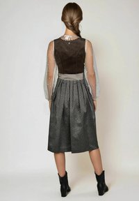 Bruine bustier met doorzichtige, versierde mouwen; gemusterde rok met plooien; zwarte enkellaarsjes; subtiele texturen en kleuren verbeteren het ontwerp.