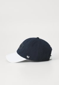 Navy blue baseball cap with a white brim, featuring a raised logo on the crown and a white embroidered accent on the side.