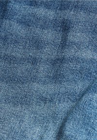 Denimstoff in einem mittleren Blauton, mit einer glatten Textur, subtilen Variationen und einem klassischen Köperbindemuster.