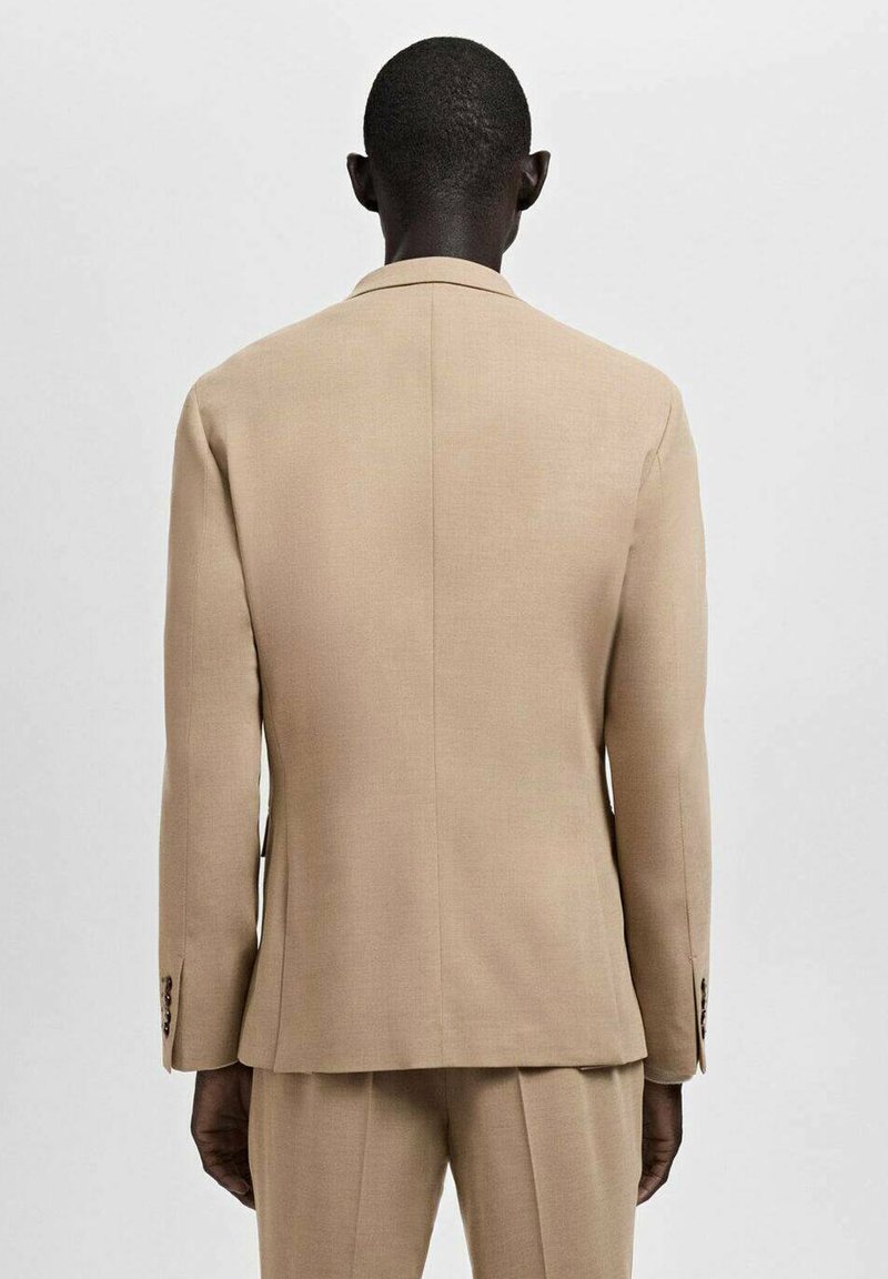 Beige suit jacket with a structured design, long sleeves, and buttoned cuffs. Smooth fabric and a straight back cut enhance its tailored look.