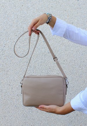 Borsa a tracolla in pelle beige con texture liscia, forma rettangolare, tracolla regolabile e dettagli in metallo argentato.