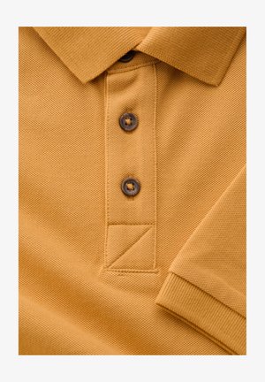Gul strikket polo med to mørke knapper, synlig krave og ribstrikket ærmekant.