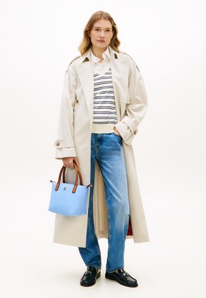 Μπεζ καμπαρντίνα με επωμίδες στους ώμους, λευκό ριγέ τοπ, μπλε τσάντα με καφέ λαβές, μπλε τζιν και μαύρα παπούτσια. Απλός σχεδιασμός.