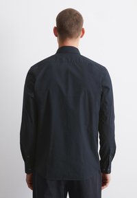 Ciemnogranatowa koszula z długim rękawem, ze standardowym kołnierzykiem, subtelną teksturą i mankietami na guziki, pokazana od tyłu na jednolitym tle.