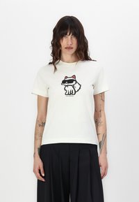 Kremfarget bomulls-t-skjorte med et grafisk design av en rev som har solbriller, med svarte og røde detaljer på designet. Korte ermer og rund hals.