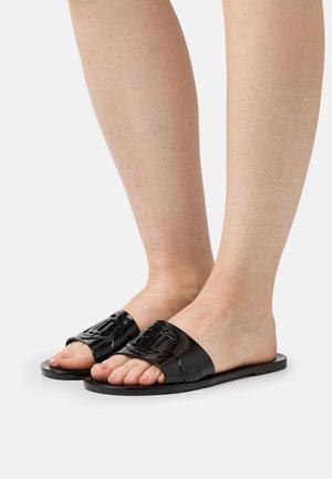 Zwarte slip-on sandalen met een brede band met uitsnijdingen. Soepele textuur en platte zool, die de tenen en voeten tonen.