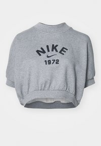 Pelēks īss svārks ar augstu apkakli, ar tumši zilu uzrakstu "NIKE 1972". Izgatavots no mīksta auduma ar elastīgu jostasvietu un piedurknēm.