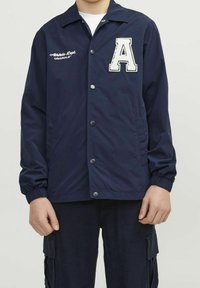 Granatowa kurtka na guziki, z elastycznymi mankietami i haftem „Athletic Dept. Originals”. Posiada dużą, białą literę „A”.