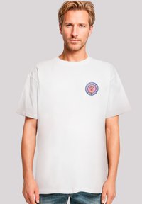 Weißes Baumwoll-T-Shirt mit einem runden Logo-Design in Pink und Lila auf der linken Brustseite, mit lässiger Passform und kurzen Ärmeln.