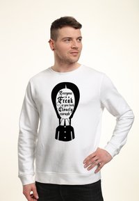 Bílá mikina s kapucí, která má černý grafický design hlavy s textem "Každý je podivín, pokud se podíváte dostatečně blízko." Text má složité detaily.