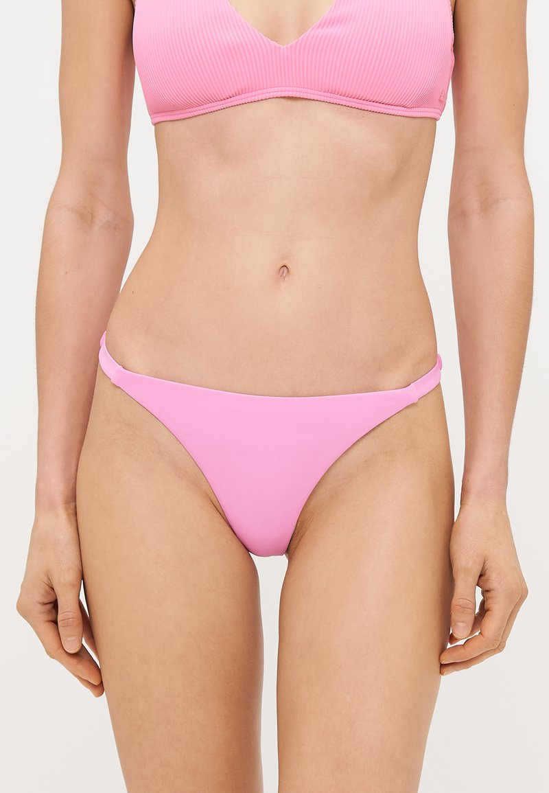 Ružičasti donji dio bikinija sa glatkom teksturom, s tankim bočnim trakama i minimalnim dizajnom pokrivanja. Nema uzoraka ili detalja od hardvera.