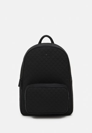 Mochila preta feita de tecido acolchoado, com um compartimento principal com fecho e um bolso frontal com fecho. Parte superior arredondada com uma pega acolchoada.