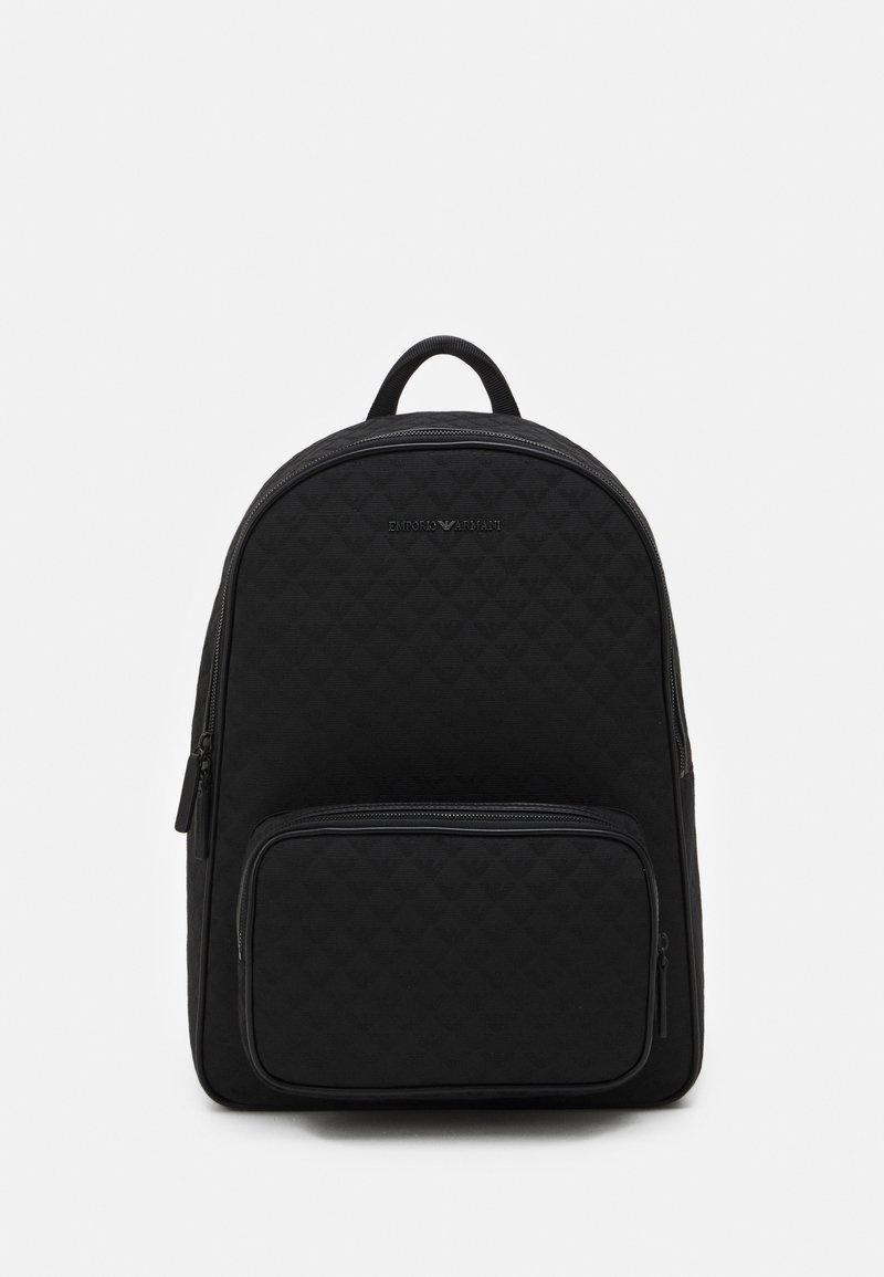 Sac à dos noir en tissu matelassé, doté d'un compartiment principal zippé et d'une poche frontale zippée. Dessus arrondi avec une poignée rembourrée.