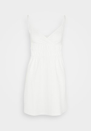 Bela poletna obleka z tankimi naramnicami, V-izrezom in zbranim pasom. Narejena iz lahkotnega blaga z rahlim teksturiranim vzorcem.